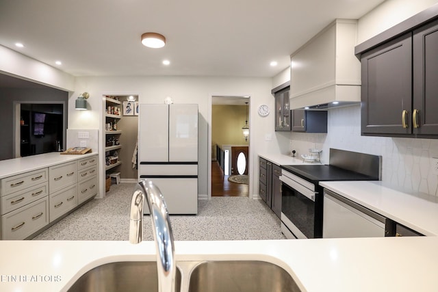 kitchen featuring electric stove, light countertops, freestanding refrigerator, decorative backsplash, and custom range hood