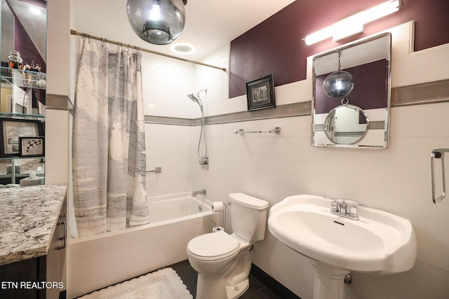 full bathroom with shower / bath combination with curtain, a sink, and toilet