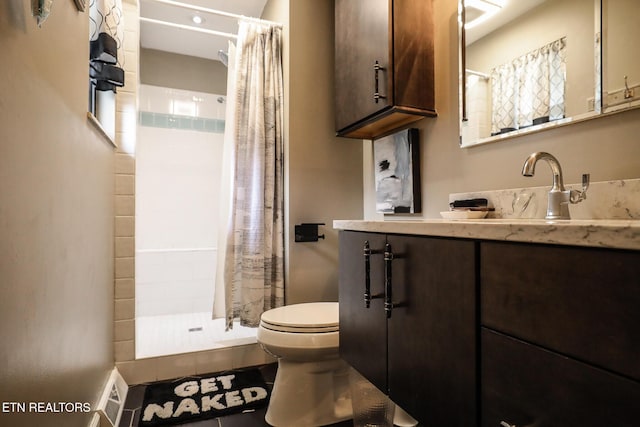 bathroom featuring vanity, a tile shower, and toilet