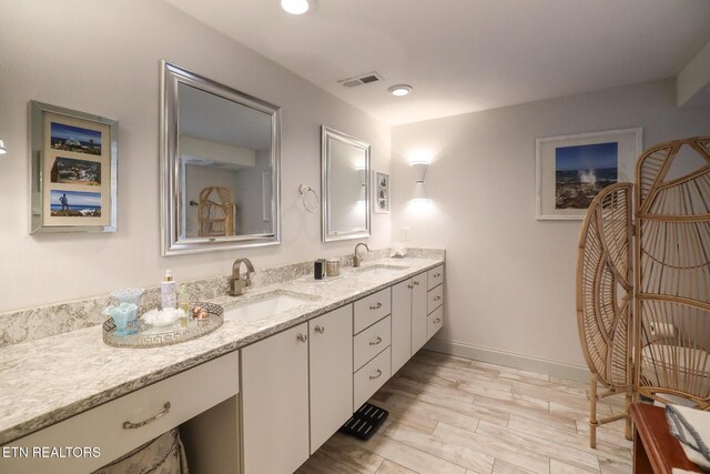 full bathroom featuring double vanity, a sink, visible vents, and baseboards