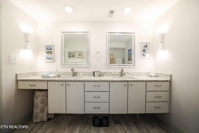 full bath featuring double vanity, visible vents, a sink, and wood finished floors