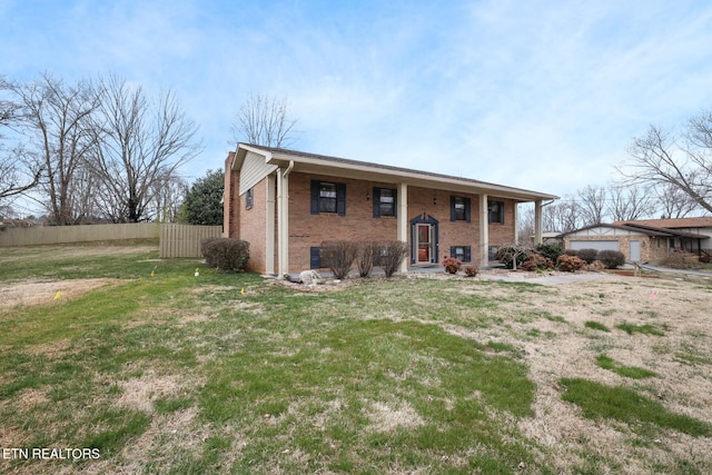 raised ranch featuring an outbuilding, fence, a front lawn, and brick siding