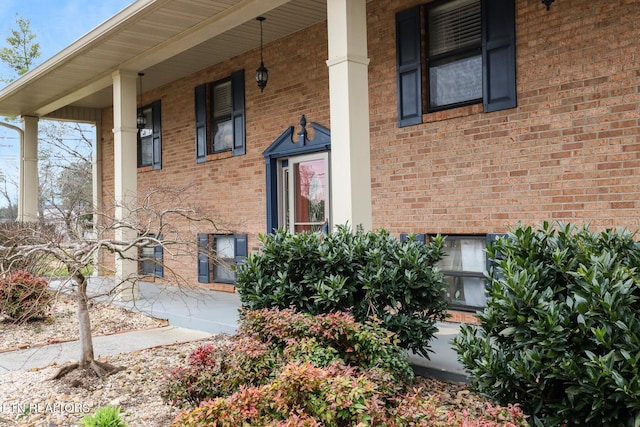 entrance to property with covered porch and brick siding