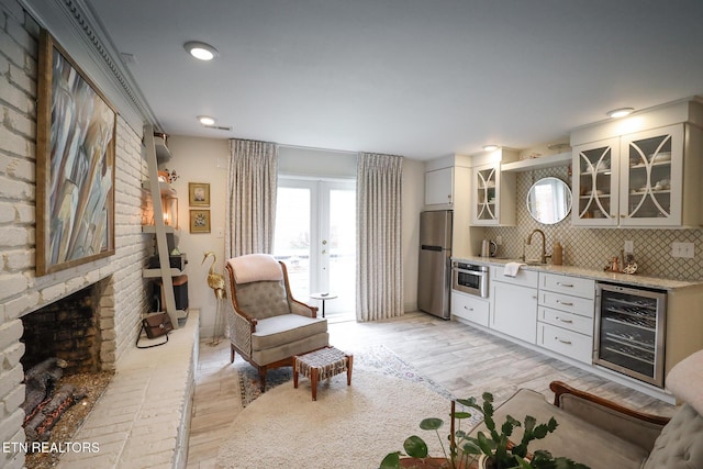 interior space with light wood finished floors, wine cooler, a fireplace, and french doors