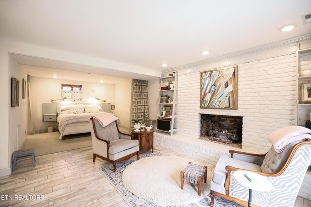 bedroom with a brick fireplace, wood finished floors, visible vents, and recessed lighting