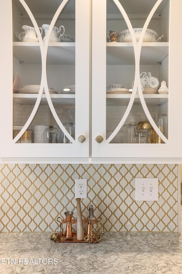 room details featuring white cabinets and decorative backsplash