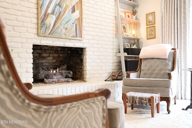 living area with a brick fireplace and carpet