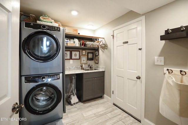 laundry area featuring cabinet space, stacked washer and clothes dryer, a sink, wood finish floors, and indoor wet bar