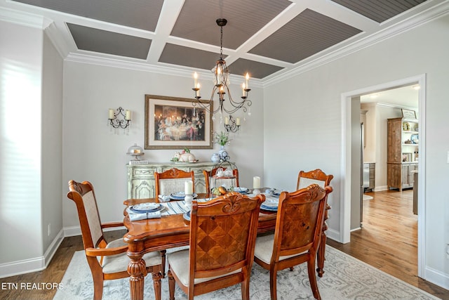 dining area featuring a notable chandelier, coffered ceiling, wood finished floors, baseboards, and crown molding