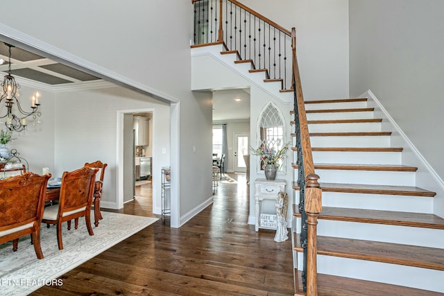 entryway with a towering ceiling, baseboards, stairway, dark wood finished floors, and an inviting chandelier