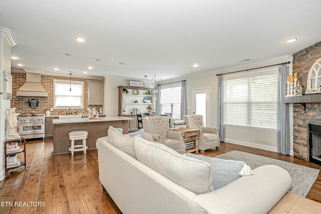 living room with a wealth of natural light, ornamental molding, a fireplace, and hardwood / wood-style floors