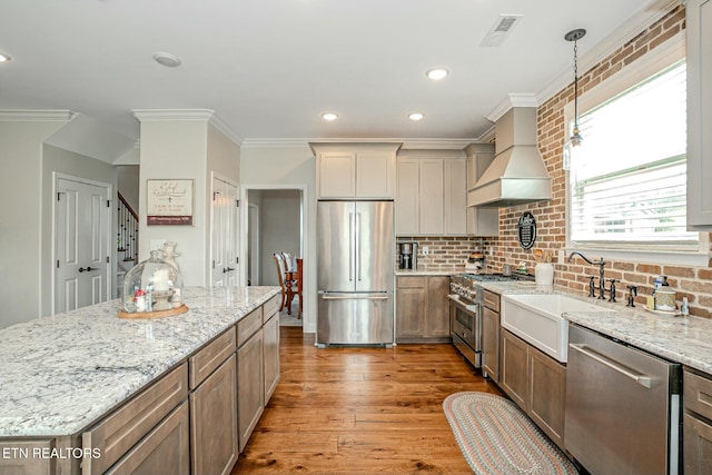 kitchen featuring visible vents, high quality appliances, wood finished floors, custom exhaust hood, and crown molding