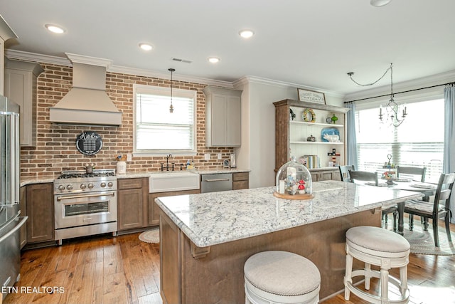 kitchen featuring stainless steel appliances, a sink, visible vents, ornamental molding, and custom exhaust hood