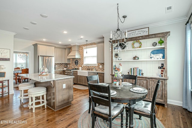 dining space featuring a healthy amount of sunlight, visible vents, wood finished floors, and ornamental molding