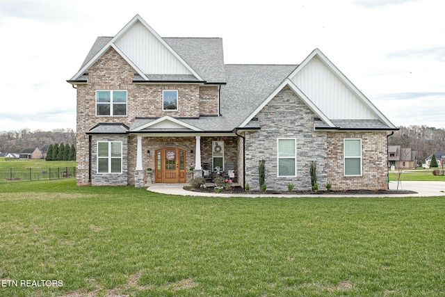 craftsman inspired home featuring a front lawn, roof with shingles, fence, and brick siding