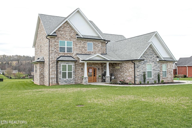 craftsman inspired home featuring stone siding, a front lawn, a shingled roof, and brick siding