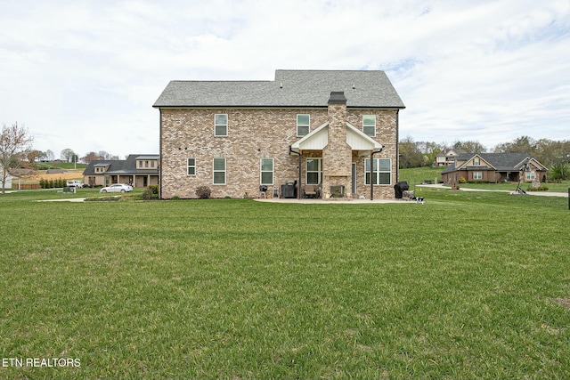 rear view of house featuring brick siding and a yard