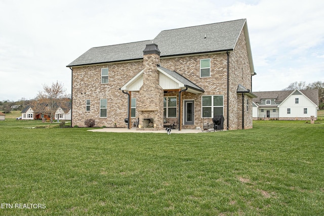 rear view of property featuring a patio, brick siding, a lawn, and a fireplace