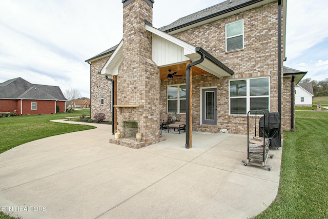 rear view of property with a ceiling fan, a lawn, a patio, a chimney, and brick siding