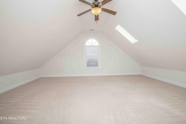 bonus room featuring carpet, vaulted ceiling with skylight, baseboards, and ceiling fan