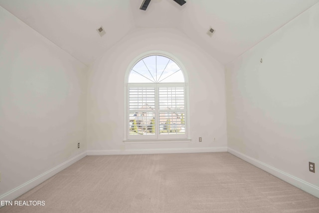 unfurnished room featuring light colored carpet, vaulted ceiling, visible vents, and baseboards