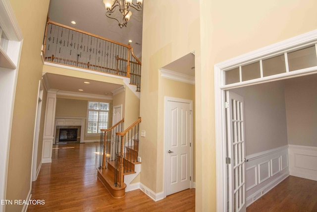 interior space featuring a decorative wall, a high ceiling, wood finished floors, stairway, and crown molding