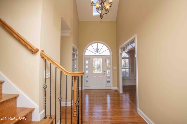 foyer with baseboards, a high ceiling, stairway, and wood finished floors