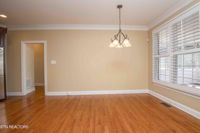 empty room with light wood-style floors, visible vents, and crown molding