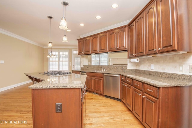 kitchen featuring light wood finished floors, a kitchen island, ornamental molding, and stainless steel appliances