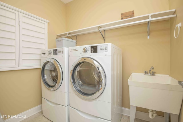 laundry room featuring laundry area, baseboards, independent washer and dryer, and a sink