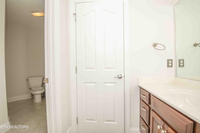 bathroom with toilet, baseboards, vanity, and tile patterned floors