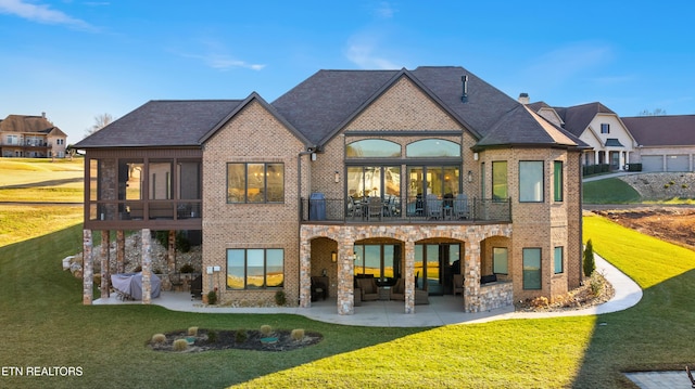 rear view of house with a balcony, a patio area, and brick siding