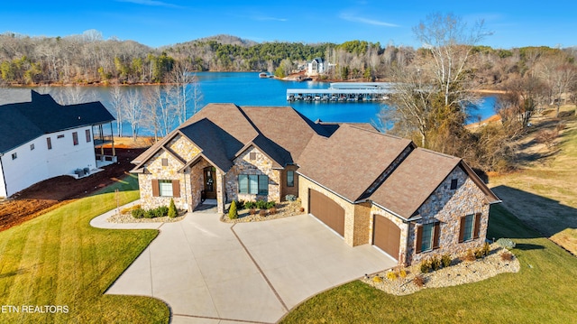 view of front of home with a water view, stone siding, concrete driveway, and a front yard