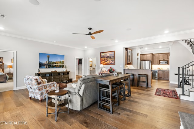 living room with baseboards, visible vents, ornamental molding, wood finished floors, and stairs