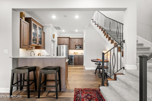 kitchen with wine cooler, a breakfast bar area, light wood-style flooring, stainless steel appliances, and visible vents