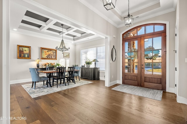 foyer featuring baseboards, coffered ceiling, dark wood-style flooring, an inviting chandelier, and crown molding