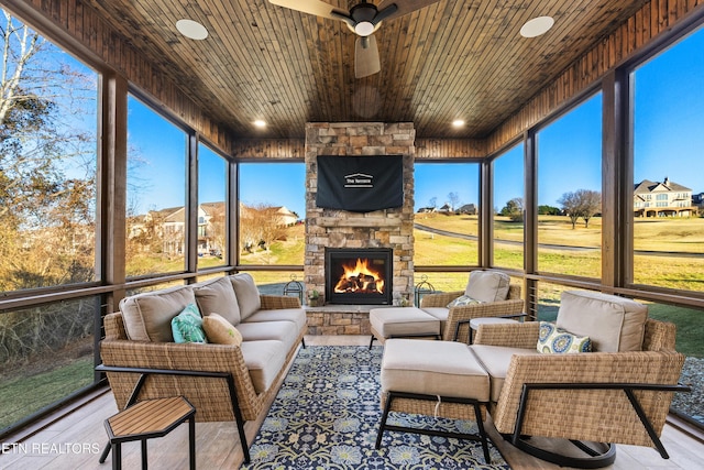 sunroom / solarium featuring ceiling fan, an outdoor stone fireplace, and wood ceiling