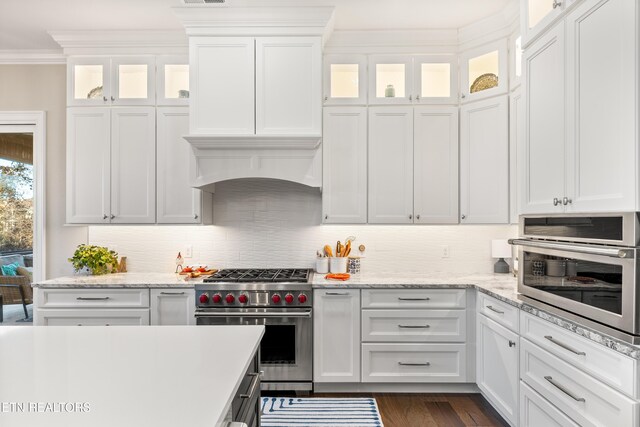 kitchen featuring stainless steel appliances, white cabinets, ornamental molding, backsplash, and dark wood finished floors