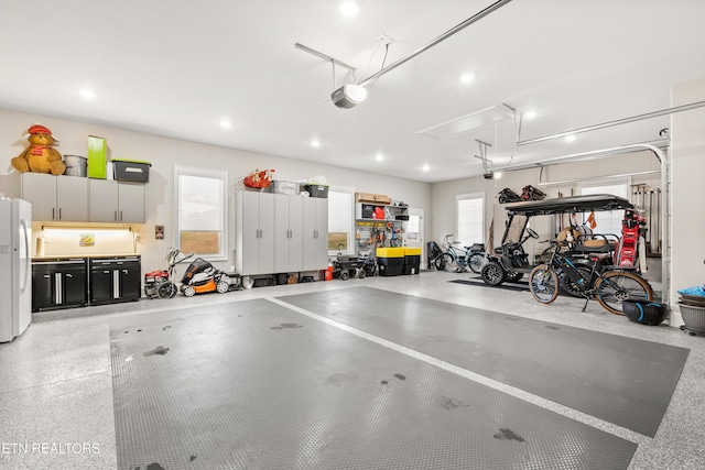 garage featuring recessed lighting, freestanding refrigerator, and a garage door opener