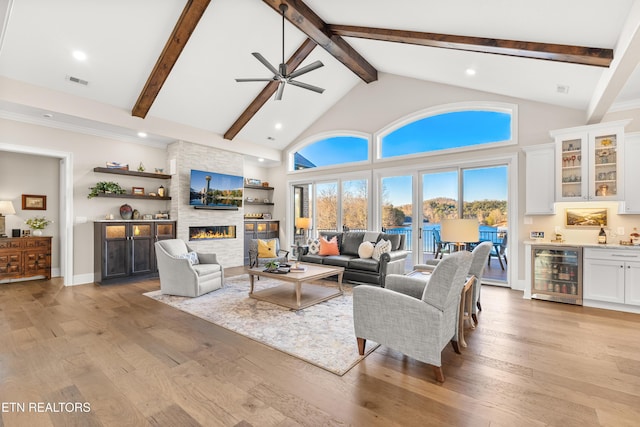 living area featuring a fireplace, a dry bar, light wood finished floors, visible vents, and beverage cooler