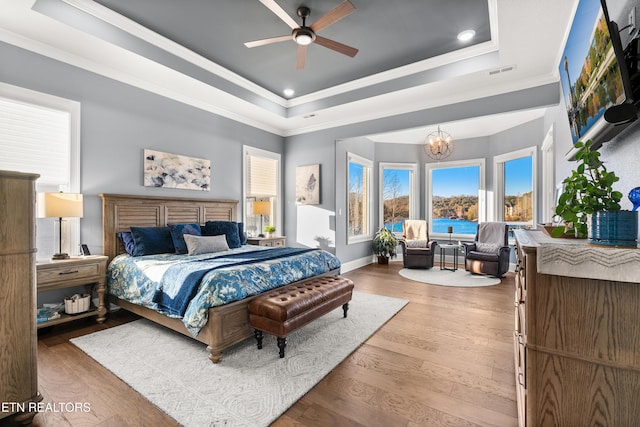 bedroom with visible vents, a tray ceiling, wood-type flooring, and ornamental molding