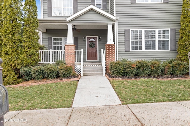 property entrance with covered porch, brick siding, and a lawn