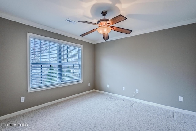 carpeted empty room with a ceiling fan, visible vents, crown molding, and baseboards