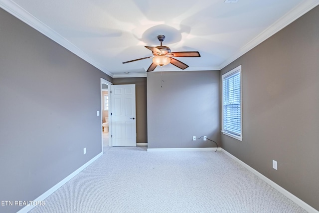 spare room with ornamental molding, light colored carpet, baseboards, and a ceiling fan