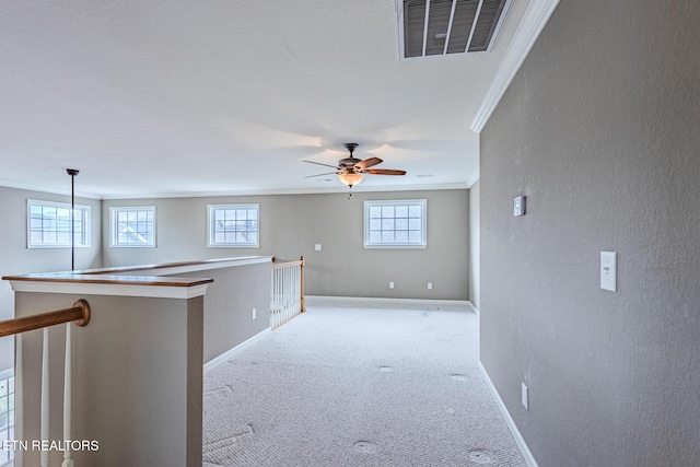 empty room with light carpet, ornamental molding, plenty of natural light, and visible vents