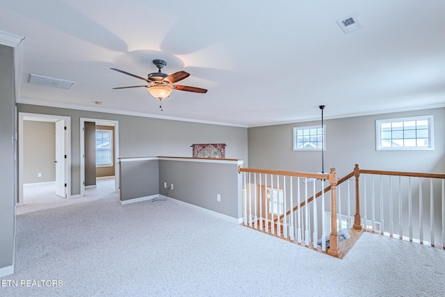 unfurnished room with baseboards, carpet flooring, visible vents, and crown molding