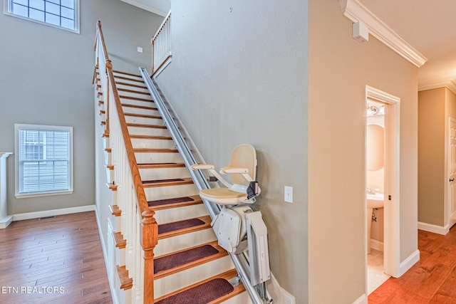 stairway featuring crown molding, baseboards, and wood finished floors