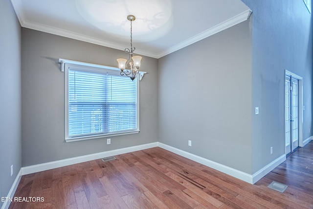 unfurnished room featuring visible vents, crown molding, a notable chandelier, and wood finished floors