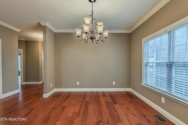 empty room featuring visible vents, crown molding, baseboards, and wood finished floors