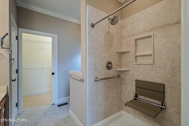 full bath with vanity, baseboards, a tile shower, a walk in closet, and crown molding